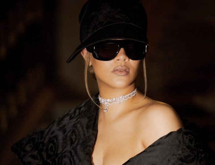 Die Sängerin Rihanna mit dunkler Brille, dunkler Mütze und dunklem Oberteil blickt an der Kamera vorbei.